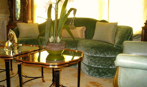A living room with green furniture and gold tables