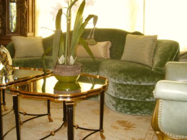 A living room with green furniture and a gold table