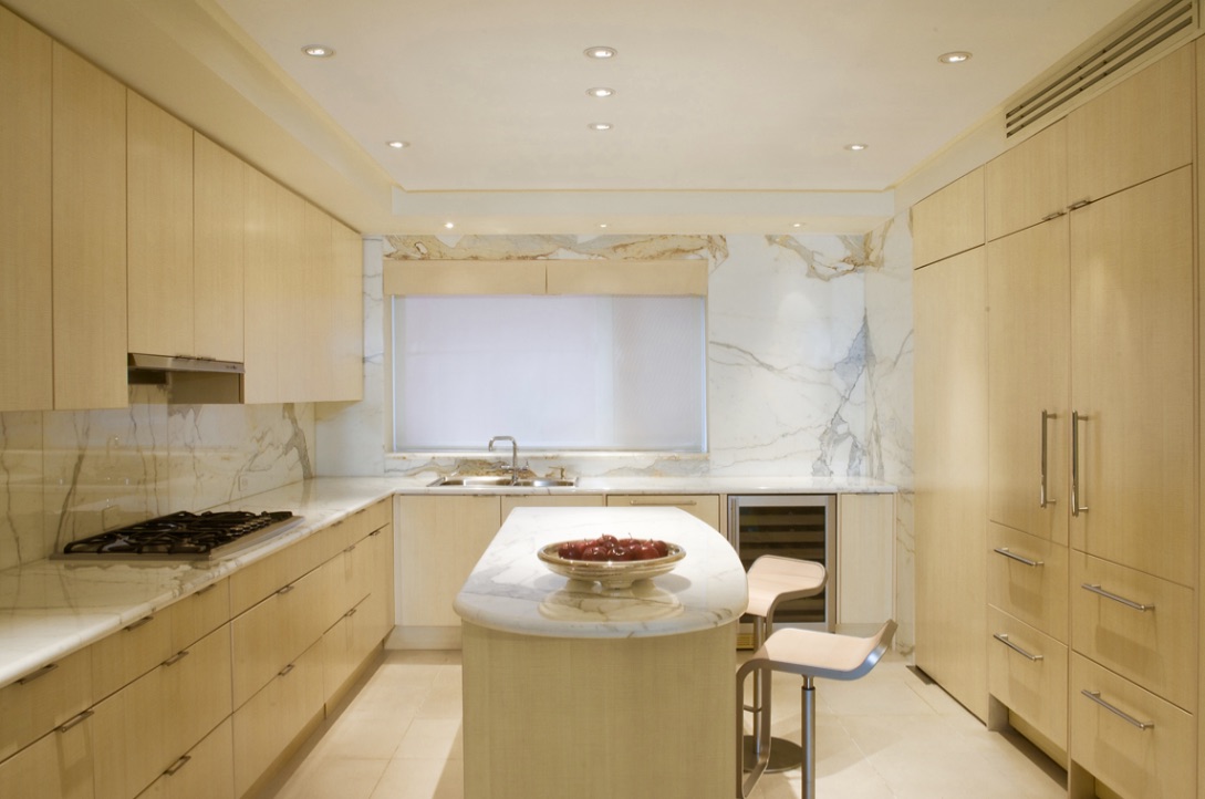 A kitchen with white cabinets and marble counter tops.
