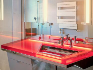 A bathroom with a red counter and sink.
