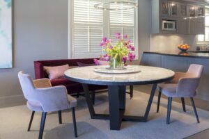 A dining room table with pink pillows and flowers in the center.