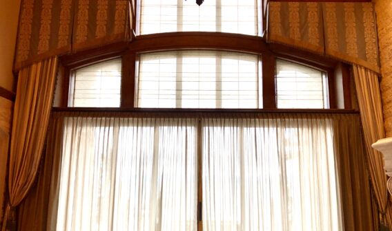 A chandelier hangs above the windows of a large room.