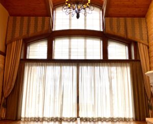 A chandelier hangs above the windows of a large room.